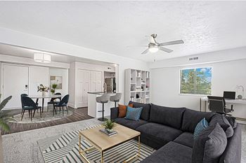 An enlarged living room with a grey couch, a coffee table, and a dining table with chairs 