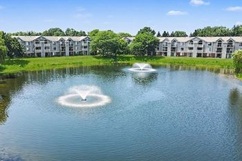 Pond with fountains and apartment buildings beyond