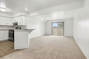 Lansing apartment for rent - A kitchen with white cabinets and a spacious living room with a sliding glass door to a balcony at Canal Club Apartments in Lansing, MI