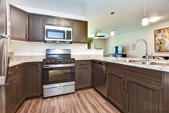 A kitchen with brown cabinets and a stainless steel refrigerator