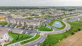 Maize apartment for rent - A bird's eye view of a residential area with houses, a roundabout, and a parking lot.