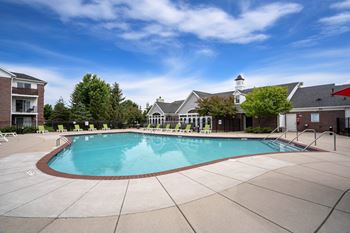 A large outdoor swimming pool surrounded by a concrete patio and buildings