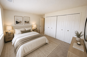 Wixom apartment for rent - A bedroom with a large bed, two nightstands with lamps, a wardrobe, and a rug.