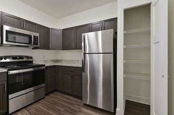 A kitchen with a stainless steel refrigerator and dark brown cabinets