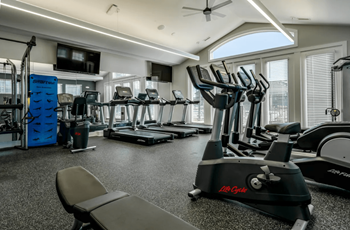 A gym with cardio equipment and a flat screen tv