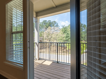 A sliding glass door opens to a balcony with a view of the woods