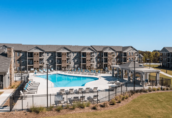 A large swimming pool with chaise lounge chairs and a building in the background