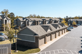 A row of houses in a parking lot with trees in the background
