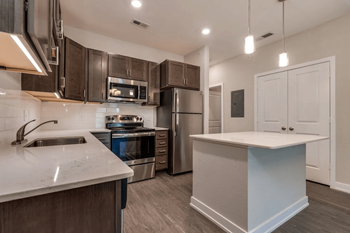 A kitchen with dark wood cabinets and white countertops