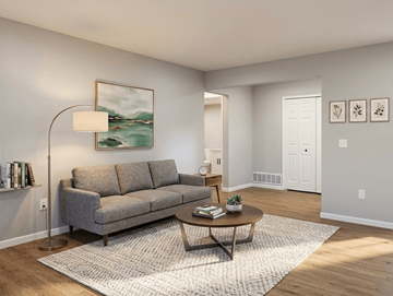 Lake Orion apartment for rent - A living room with a grey couch, a round table, and a painting on the wall.