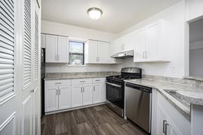 Portage townhouse for rent - A kitchen with white cabinets and a stainless steel dishwasher and oven at Foxwood and The Hermitage in Portage, MI
