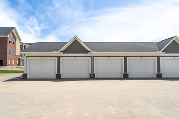 A car garage with three garages and a house in the background