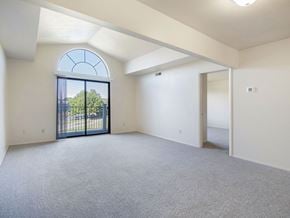 Battle Creek apartment for rent - A spacious living room with a cathedral ceiling, large arched window and a balcony with a view at Glenn Valley Apartments, Michigan, 49015