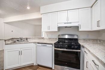 A kitchen with white cabinets and hard surface flooring