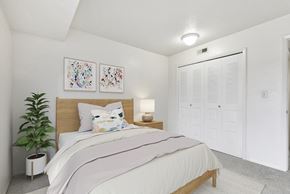 Jackson apartment for rent - A bedroom with a large closet, bed, and a potted plant at Granada Apartments, Jackson, 49202