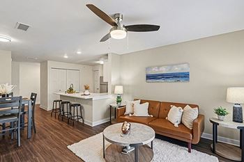 A living room with a ceiling fan and hard-surface flooring