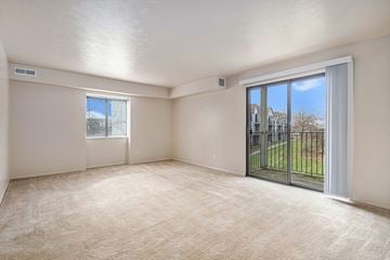South Bend apartment for rent - A room with a carpeted floor, a sliding glass door, and a window.
