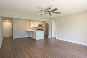Wixom apartment for rent - an empty living room with a kitchen in the background at Hillside Apartments, Michigan, 48393