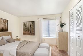 South Bend apartment for rent - A bedroom with a bed, a nightstand, a cabinet, and a closet at Irish Hills Apartments, South Bend, Indiana