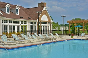 A swimming pool with chaise lounge chairs and a building in the background