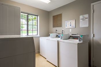 A laundry room with four washers and dryers