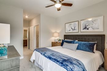 A bedroom with a large bed and a ceiling fan