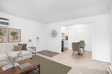 Kalamazoo apartment for rent - A living room with a couch, chair, and a table with a vase of flowers on it.