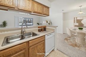 Peoria apartment for rent - A kitchen with wooden cabinets and a white dishwasher.