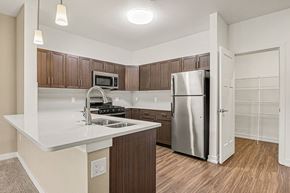 Grand Rapids apartment for rent - A kitchen with a breakfast bar and a stainless steel refrigerator at Meadowbrooke Apartment Homes in Grand Rapids, MI 49512