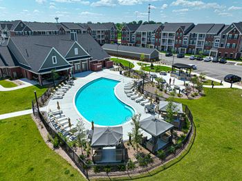 An aerial view of a resort style pool with lounge chairs and umbrellas
