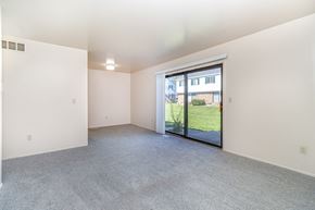 Kalamazoo townhouse for rent - A large living room with a sliding glass door leading to a green outdoor area at Mount Royal Townhomes, Michigan
