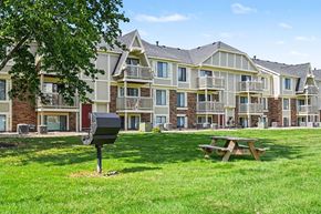 Michigan City apartment for rent - A large apartment complex with a mailbox and picnic table in front.
