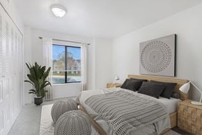 Oak Creek apartment for rent - A bedroom with a large bed and a large window with a view of the outside at Oak Shores Apartments in Oak Creek, WI