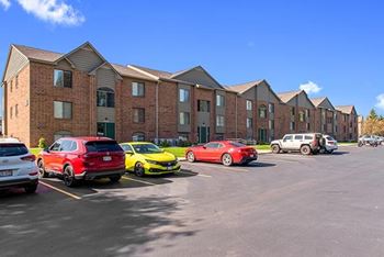 A parking lot with cars and an apartment building in the background 