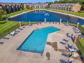 Oak Creek apartment for rent - A large swimming pool surrounded by lounge chairs and a pond with a fountain behind it at Oak Shores Apartments, Wisconsin