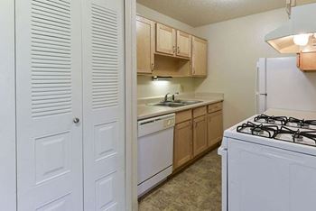 A kitchen with a white dishwasher and wooden cabinets
