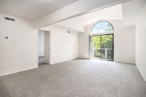 Battle Creek apartment for rent - A spacious living room with a large window, cathedral ceiling, and carpeted floor at Pine Knoll Apartments, Battle Creek, 49014