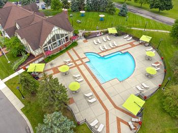 An aerial view of a resort style pool with lounge chairs and umbrellas