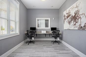 A business center with two black chairs are placed in front of a desk with a computer