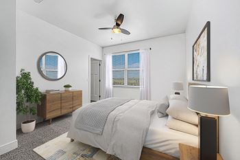 A bedroom with a bed, a ceiling fan, and a potted plant