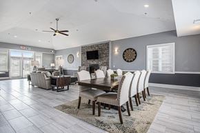 Grimes apartment for rent - A modern clubhouse dining room with a wooden table and chairs at The Reserve at The Reserve at Destination Pointe in Grimes, IA 50111