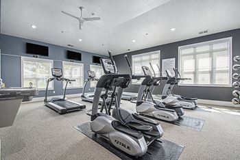 A gym with treadmills, elliptical machines, and a fan 