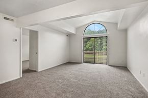 Fort Wayne apartment for rent - A room with a carpeted floor and a large window with a view of a fence and trees.