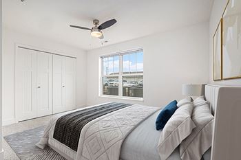 A bedroom with a large window and a ceiling fan 