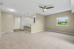 West Des Moines apartment for rent - An enlarged living room with a ceiling fan and carpeted floor at Strathmore Apartment Homes in West Des Moines, IA
