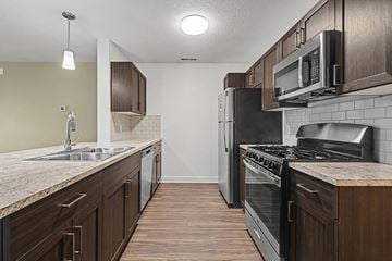 West Des Moines apartment for rent - A kitchen with dark wood cabinets and a granite counter top.