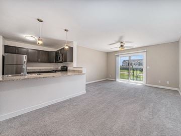 West Des Moines apartment for rent - A spacious living room with a kitchen area and sliding glass doors leading to a balcony.