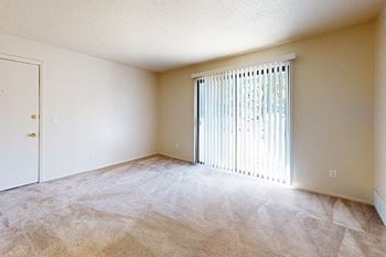 A carpeted living room leading to a private patio
