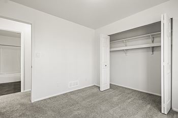 A white bedroom with a closet and a carpeted floor