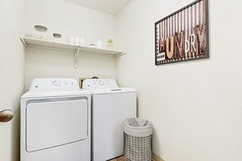 A laundry room with a washer and dryer and a shelf above 